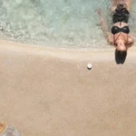 woman lies by shore of sand pool